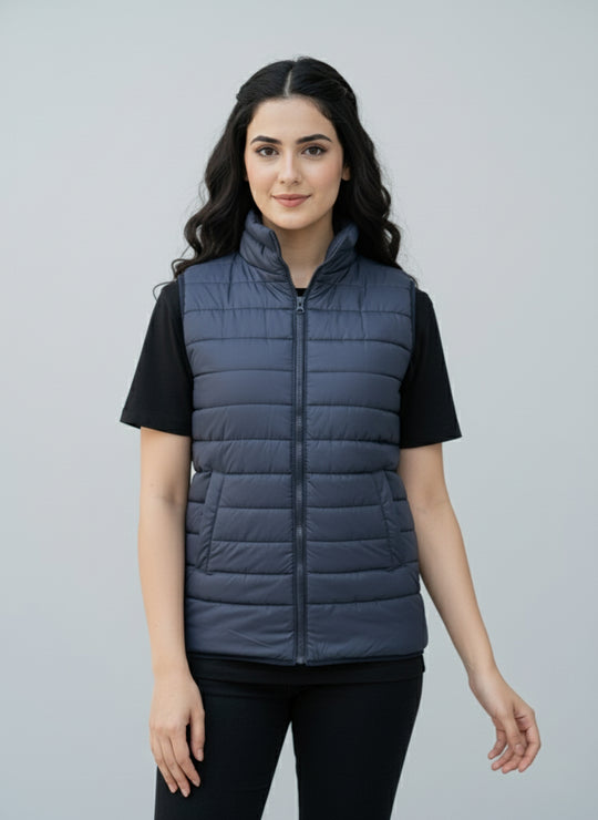 Woman wearing a blue puffer vest over a black shirt on a gray background