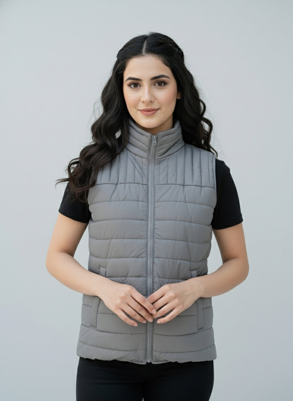 Woman wearing a gray puffer vest against a plain background