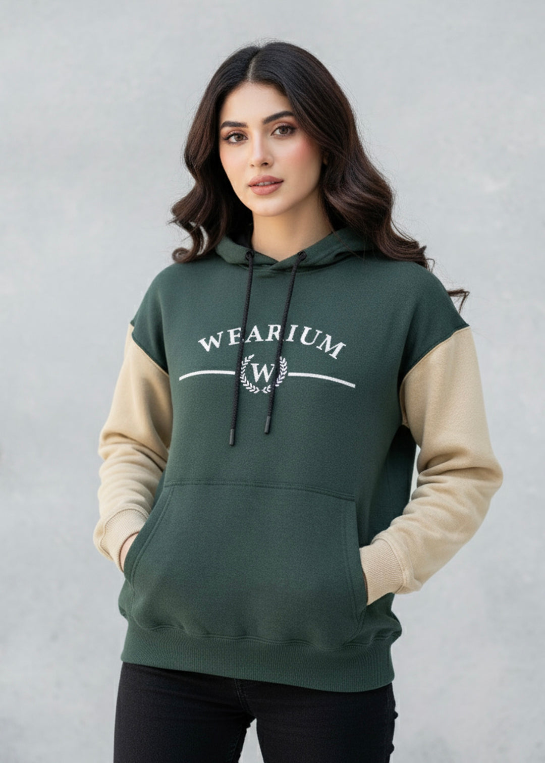 Woman wearing a green and beige hoodie with 'WEARITUM' logo on a gray background
