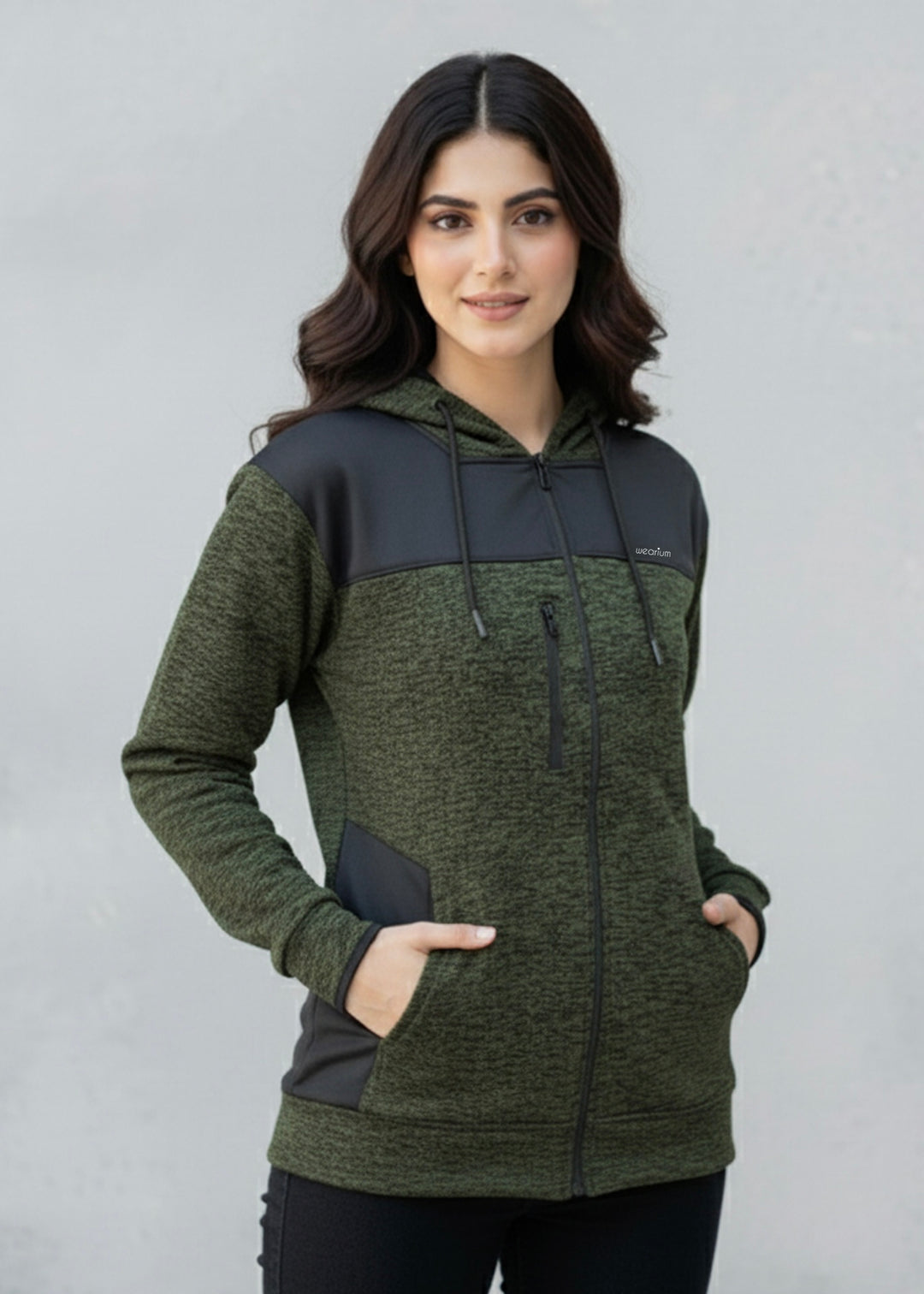 Woman wearing a green and black textured hoodie against a plain background
