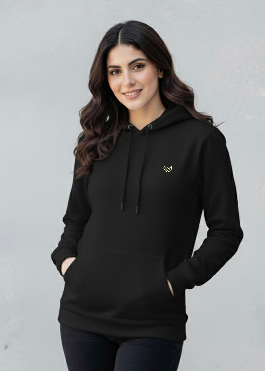 Woman wearing a black hoodie with a small logo on a gray background