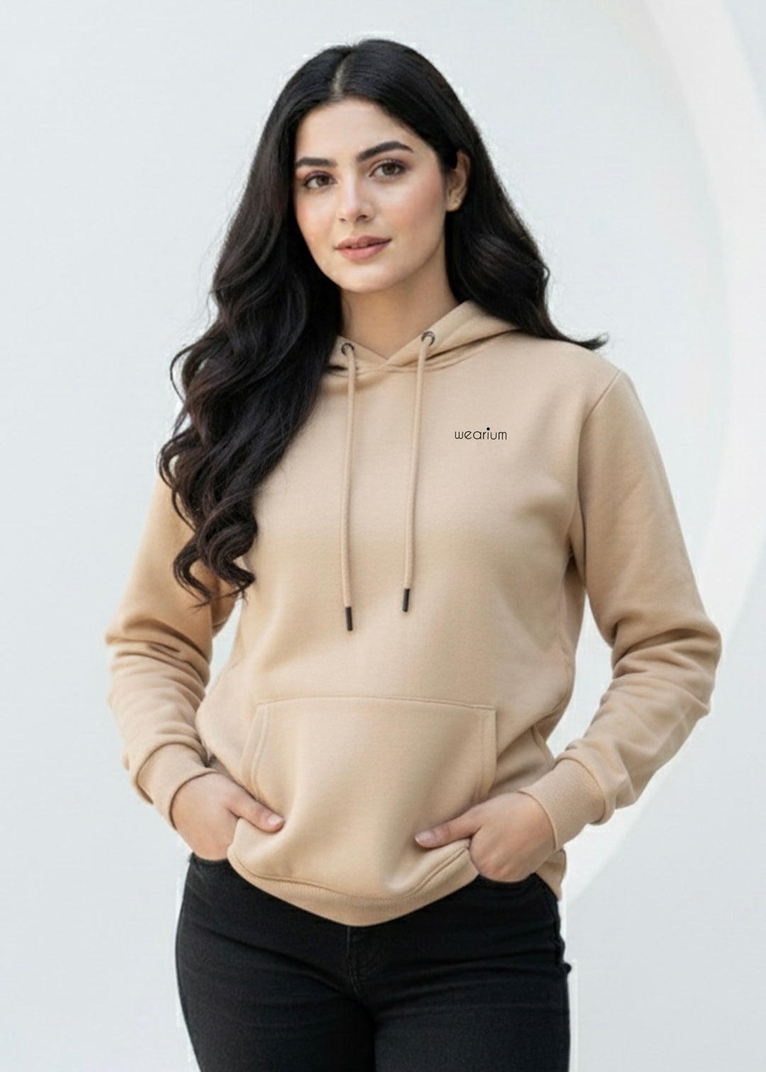 Woman wearing a beige hoodie with a brand logo on a white background