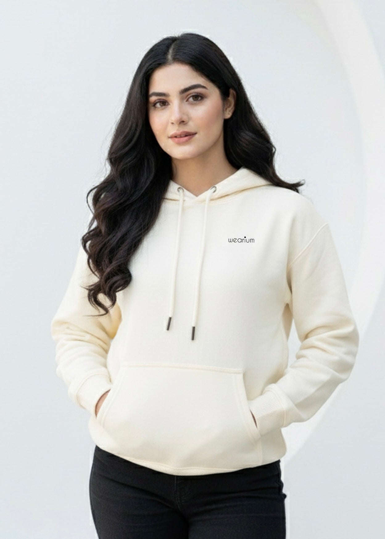 Woman wearing a cream hoodie with a brand logo on a white background