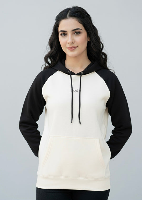 Woman wearing a black and white hoodie with a plain background