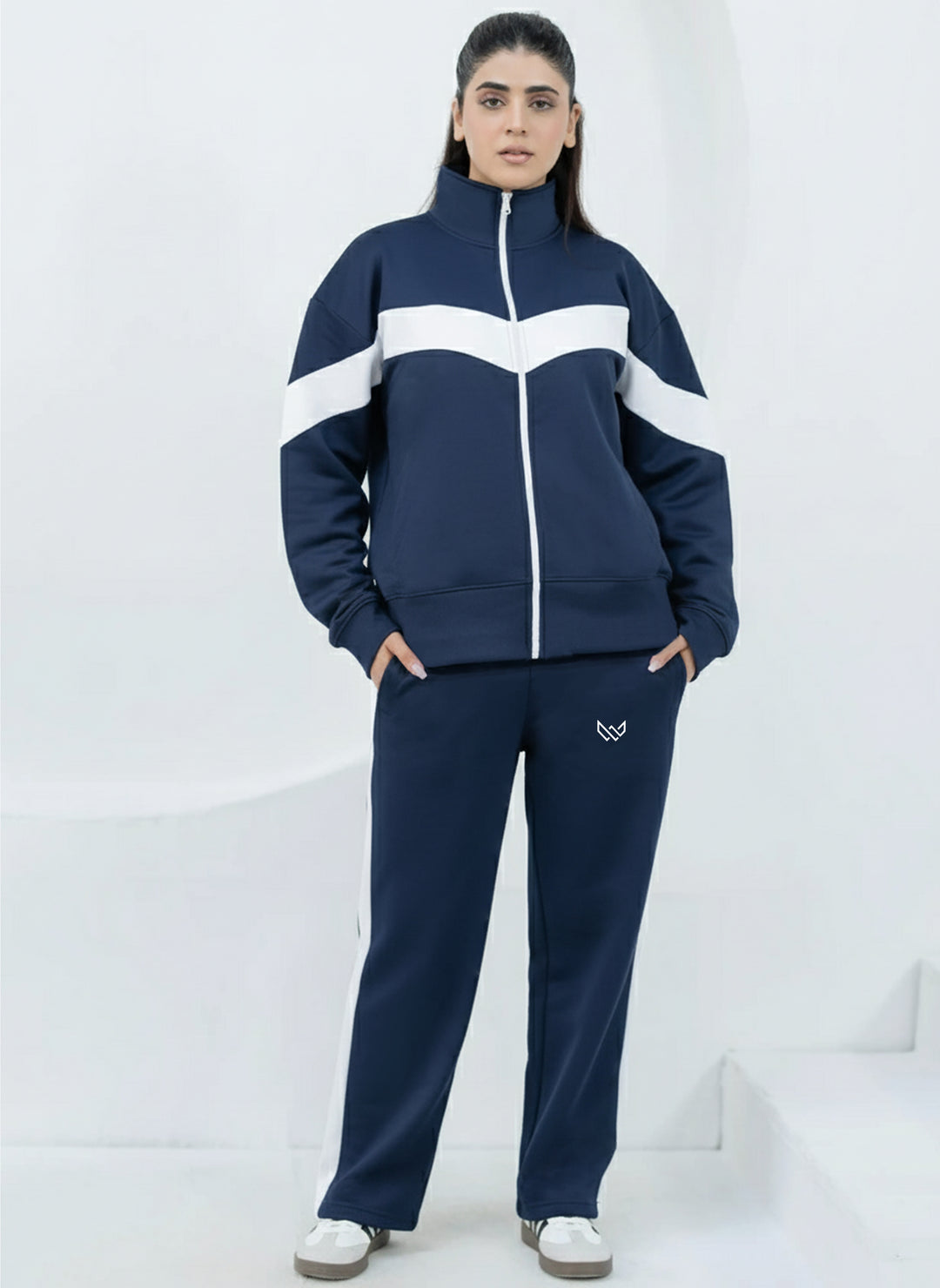 Person wearing a navy tracksuit with white stripes on a white background