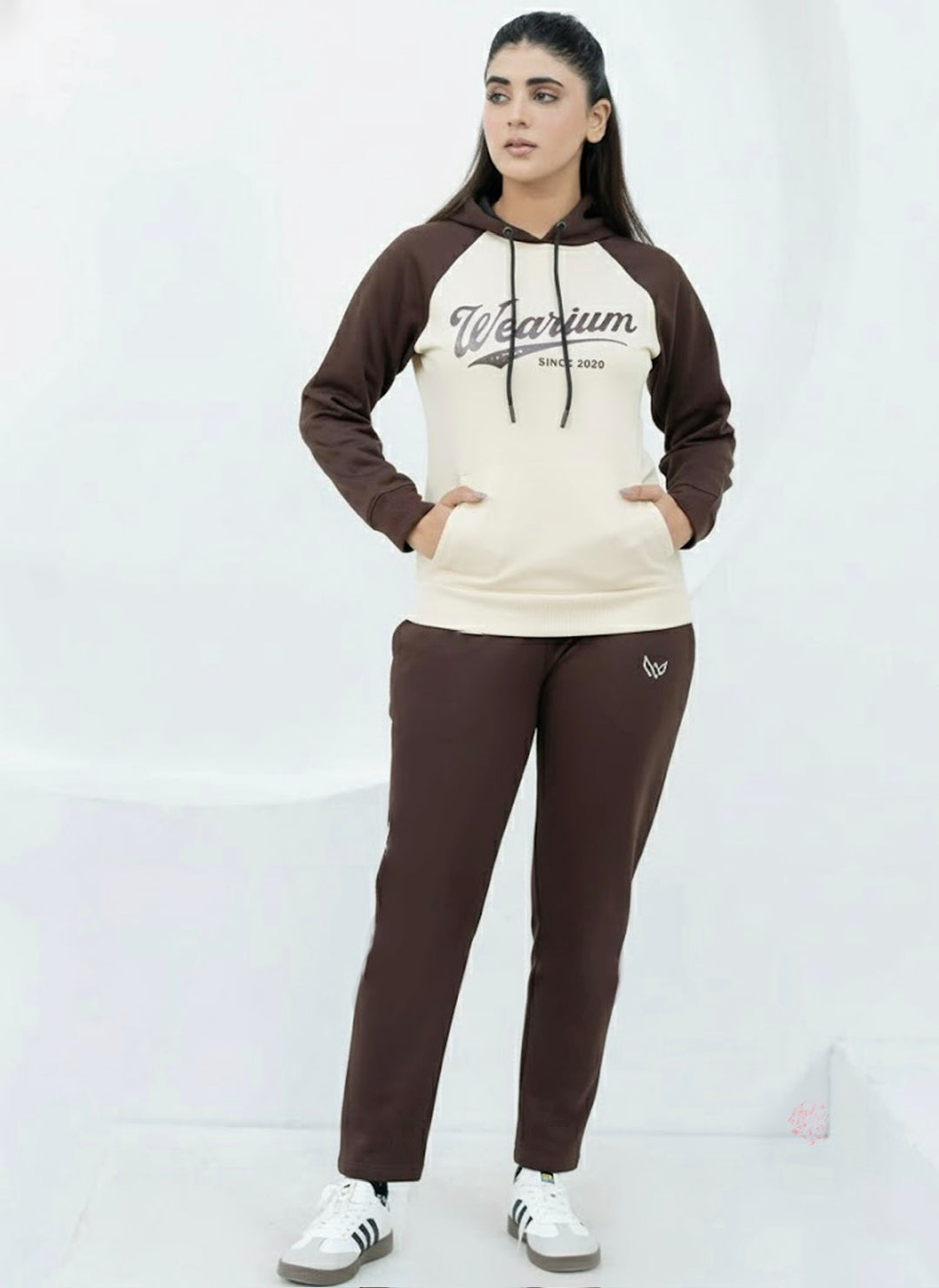Woman wearing a brown and beige twinset with hoodie matching pants on a white background