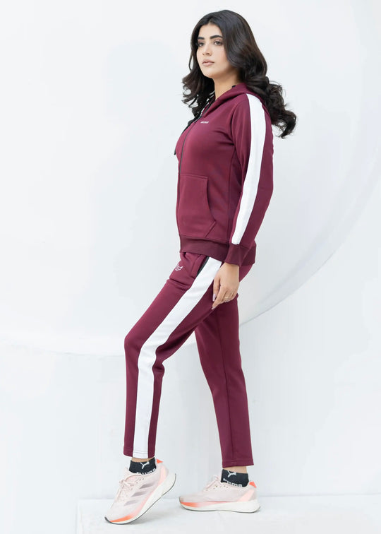 Woman wearing a maroon tracksuit with white stripes on a white background