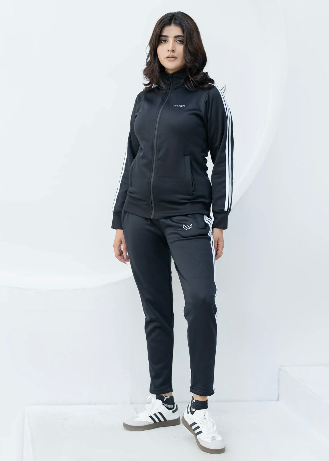 Woman wearing a black tracksuit with white stripes on a white background