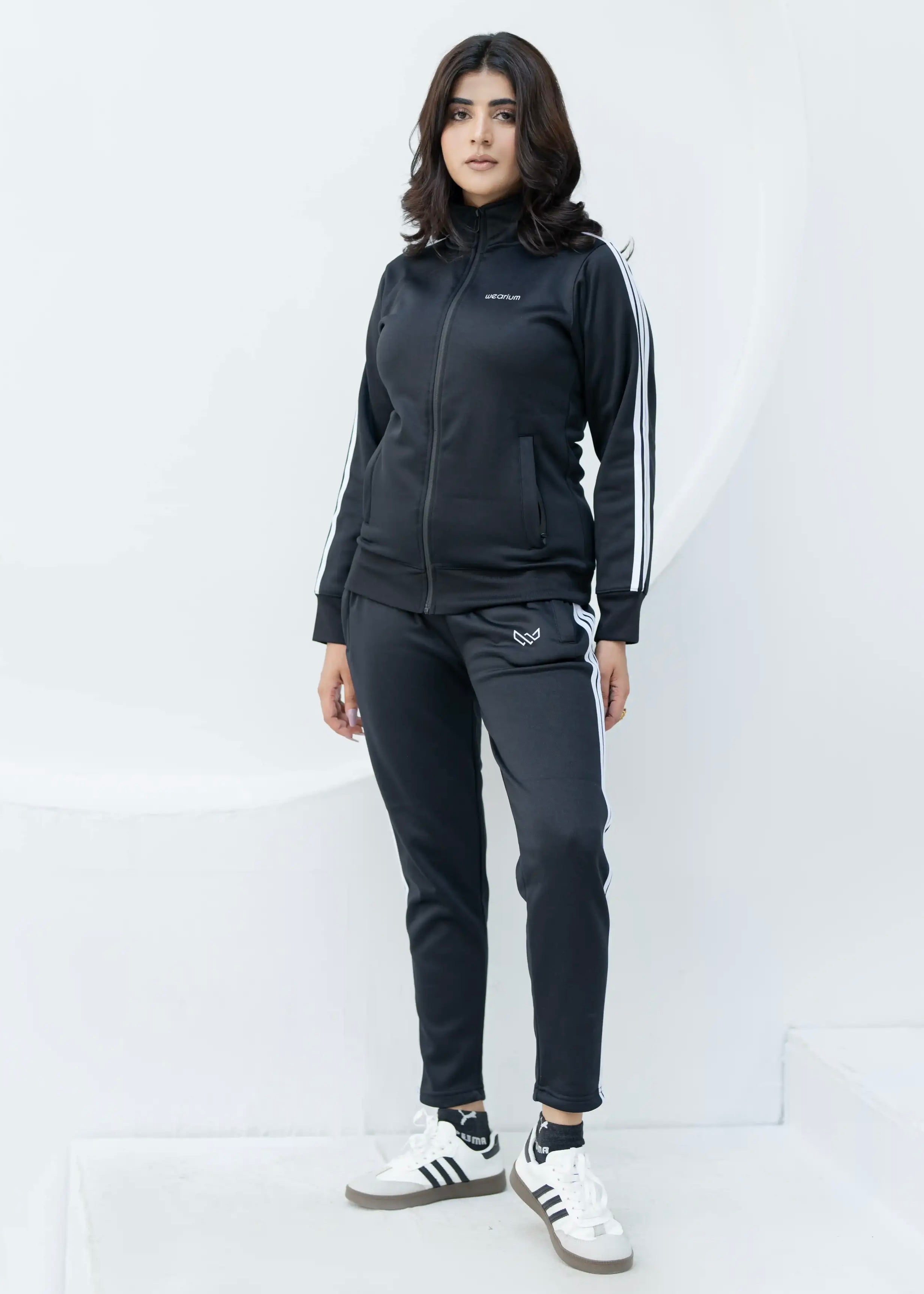 Woman wearing a black tracksuit with white stripes on a white background