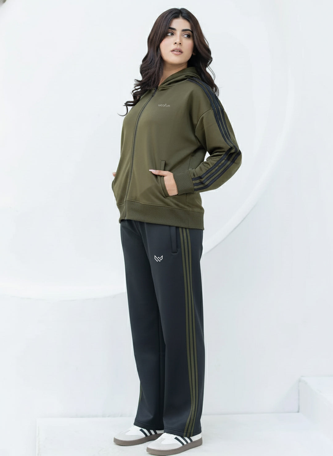 Woman wearing a green tracksuit with black pants on a white background