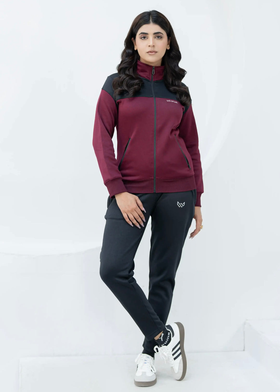 Woman wearing a maroon and black tracksuit on a white background