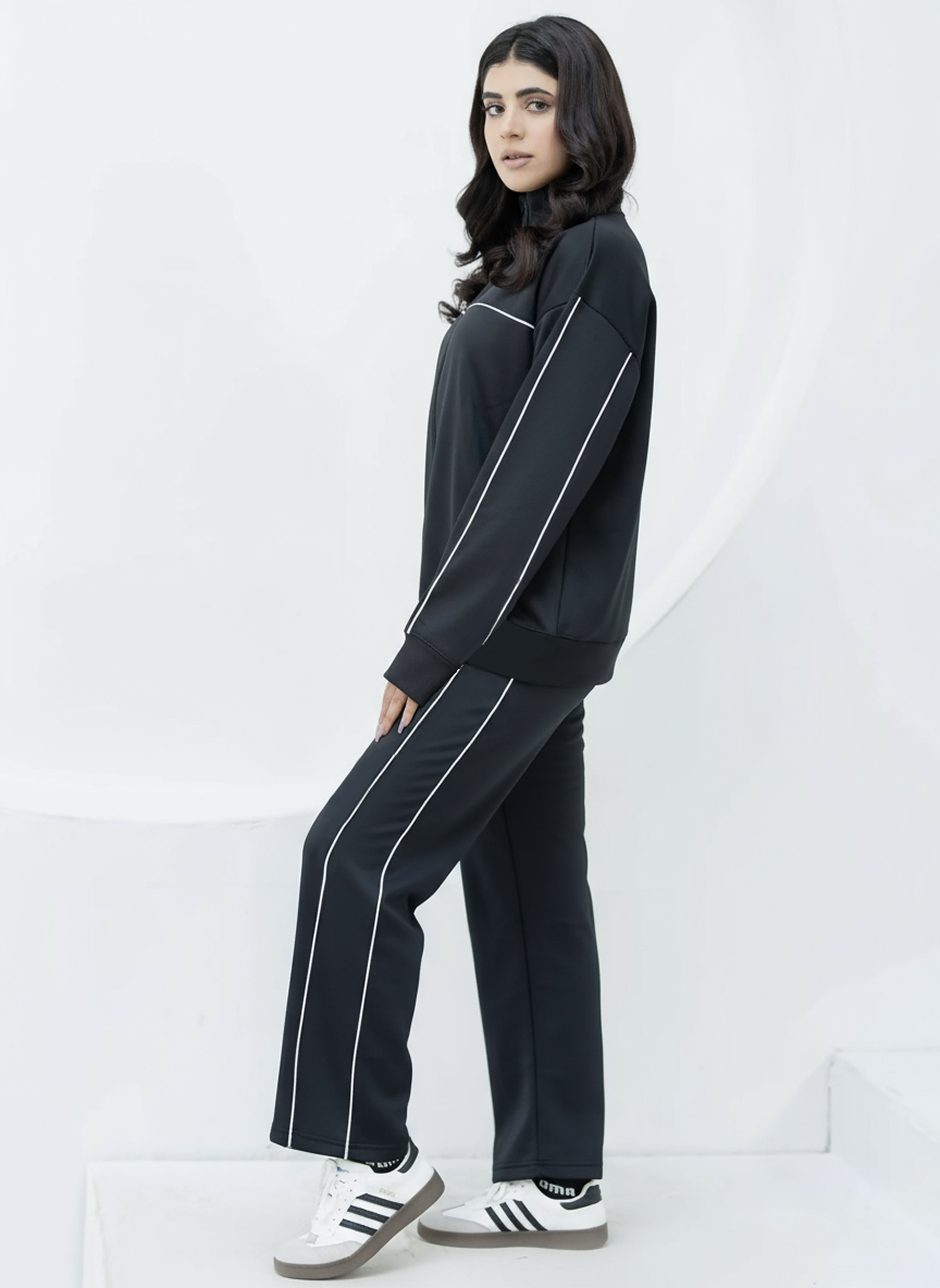 Person wearing a black tracksuit with white stripes on a white background