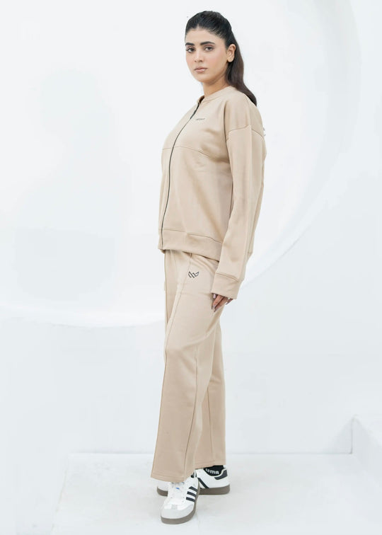 Person wearing a beige tracksuit with Adidas shoes on a white background