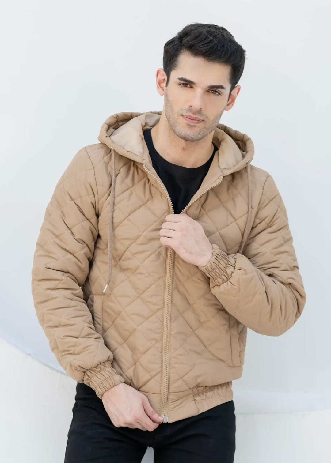 Man wearing a beige quilted jacket against a white background