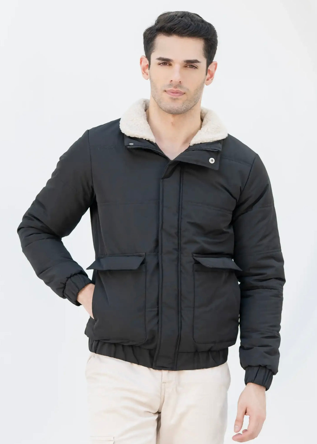 Man wearing a black jacket with a wool collar against a plain background
