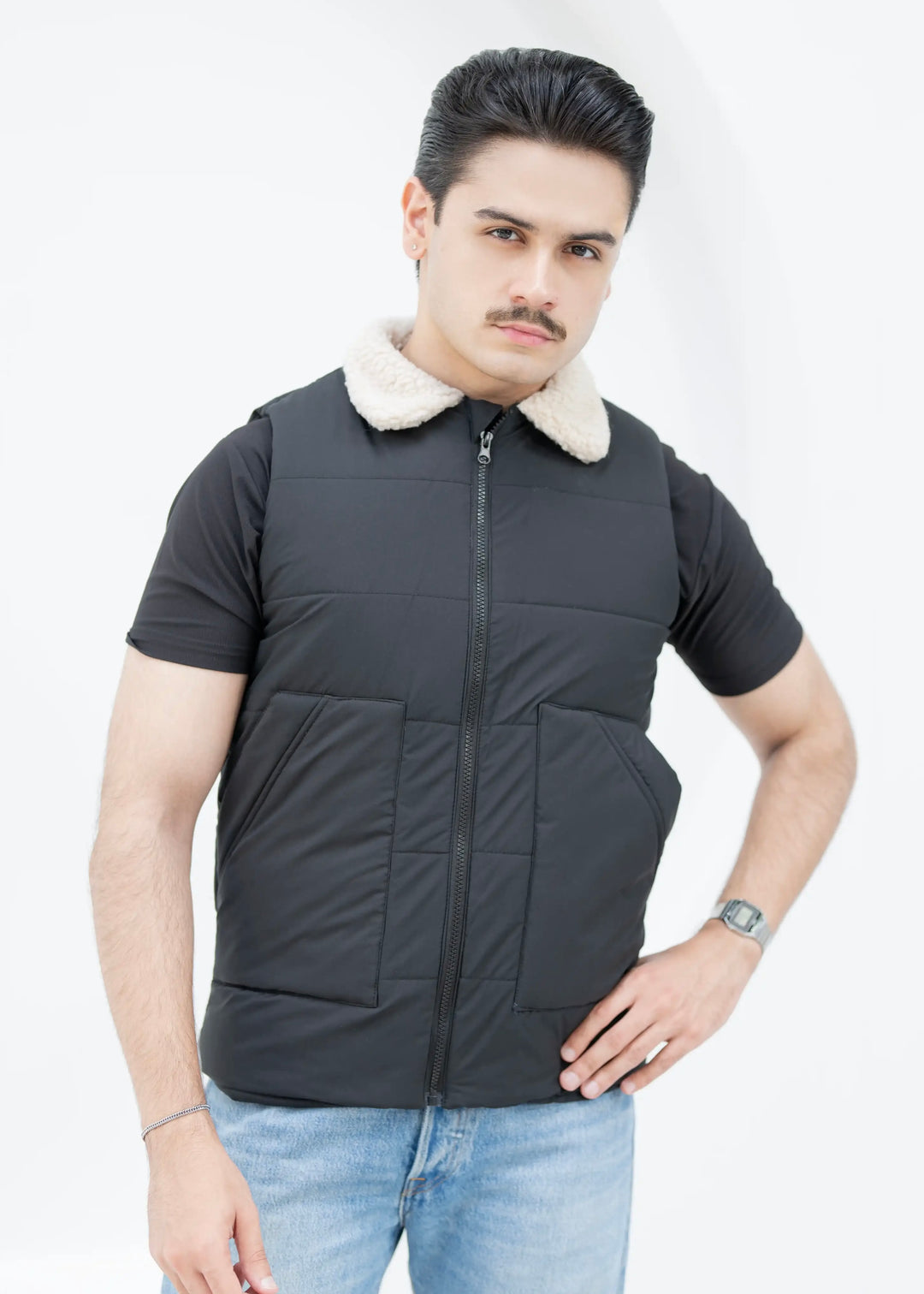 Man wearing a black puffer vest with a white fur collar on a white background