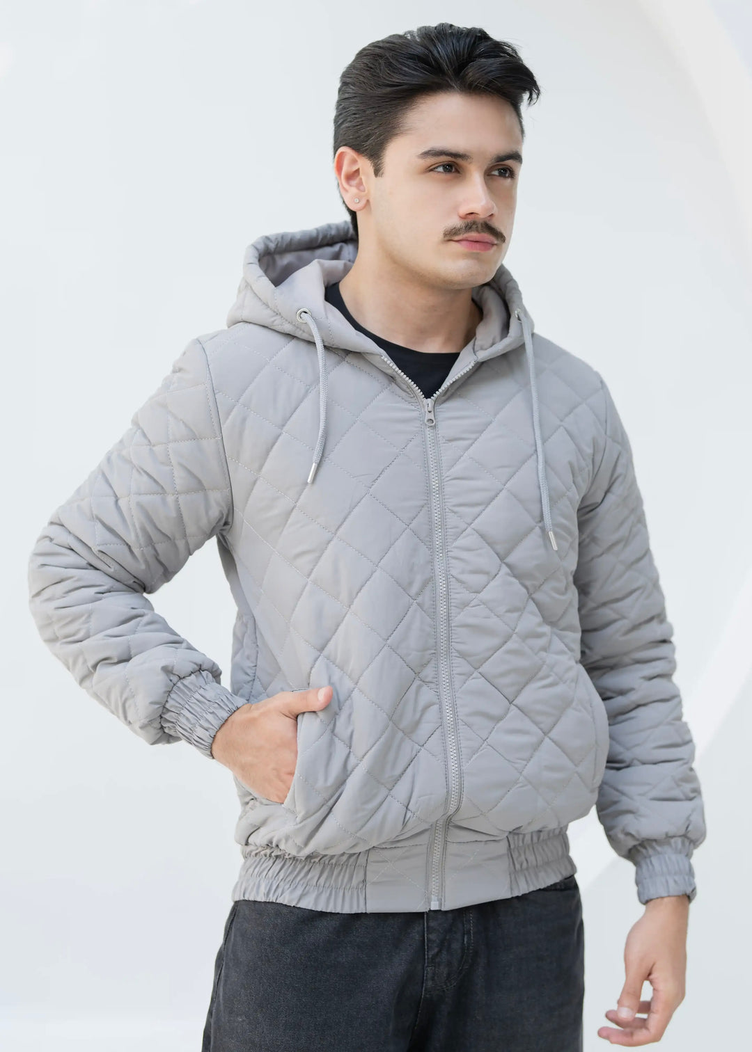Man wearing a gray quilted jacket against a white background
