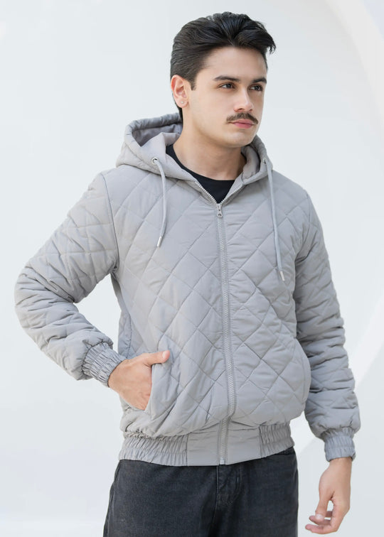 Man wearing a gray quilted jacket against a white background