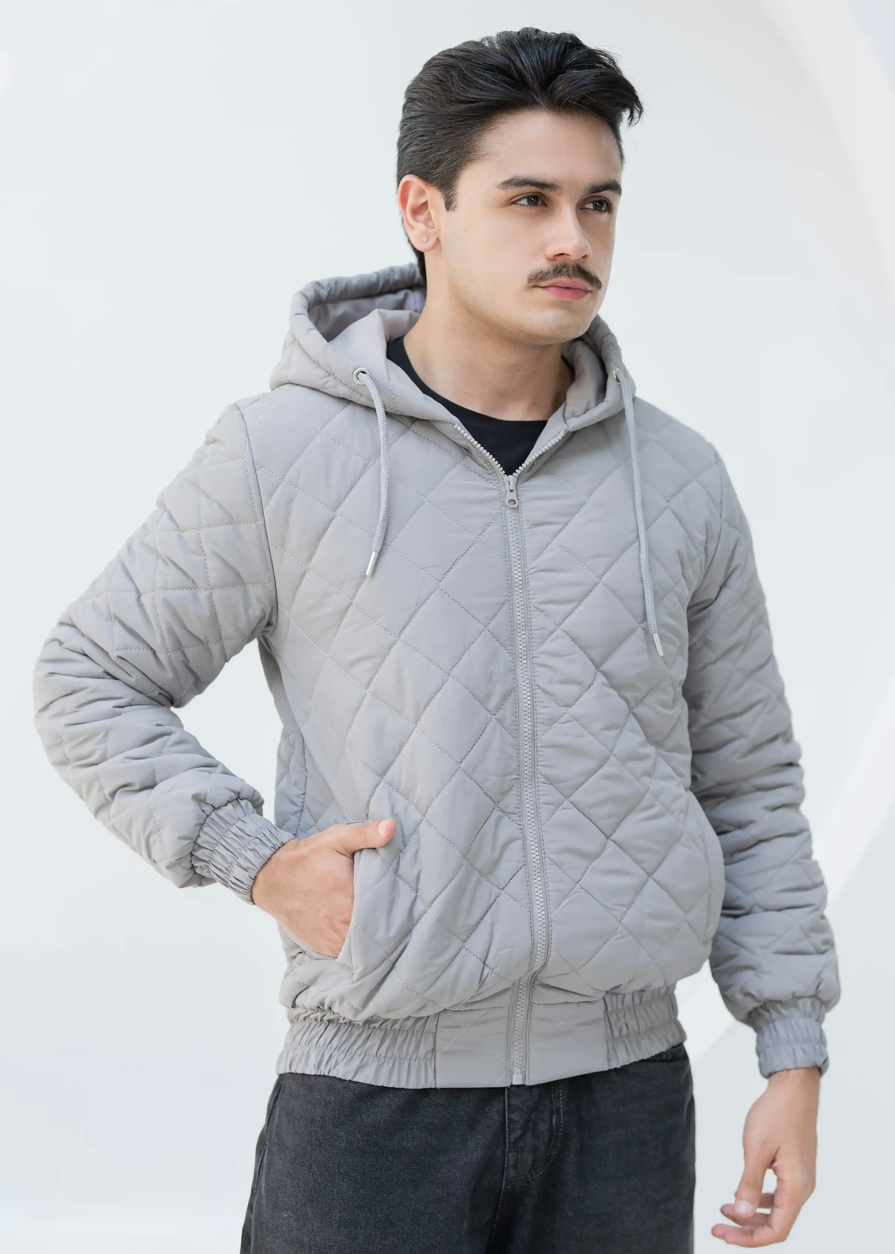 Man wearing a gray quilted jacket against a white background
