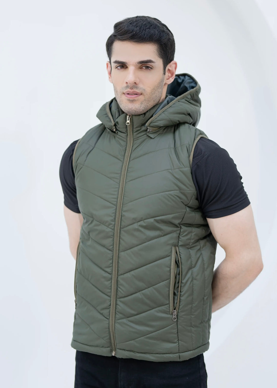 Man wearing a green quilted vest with removable hood