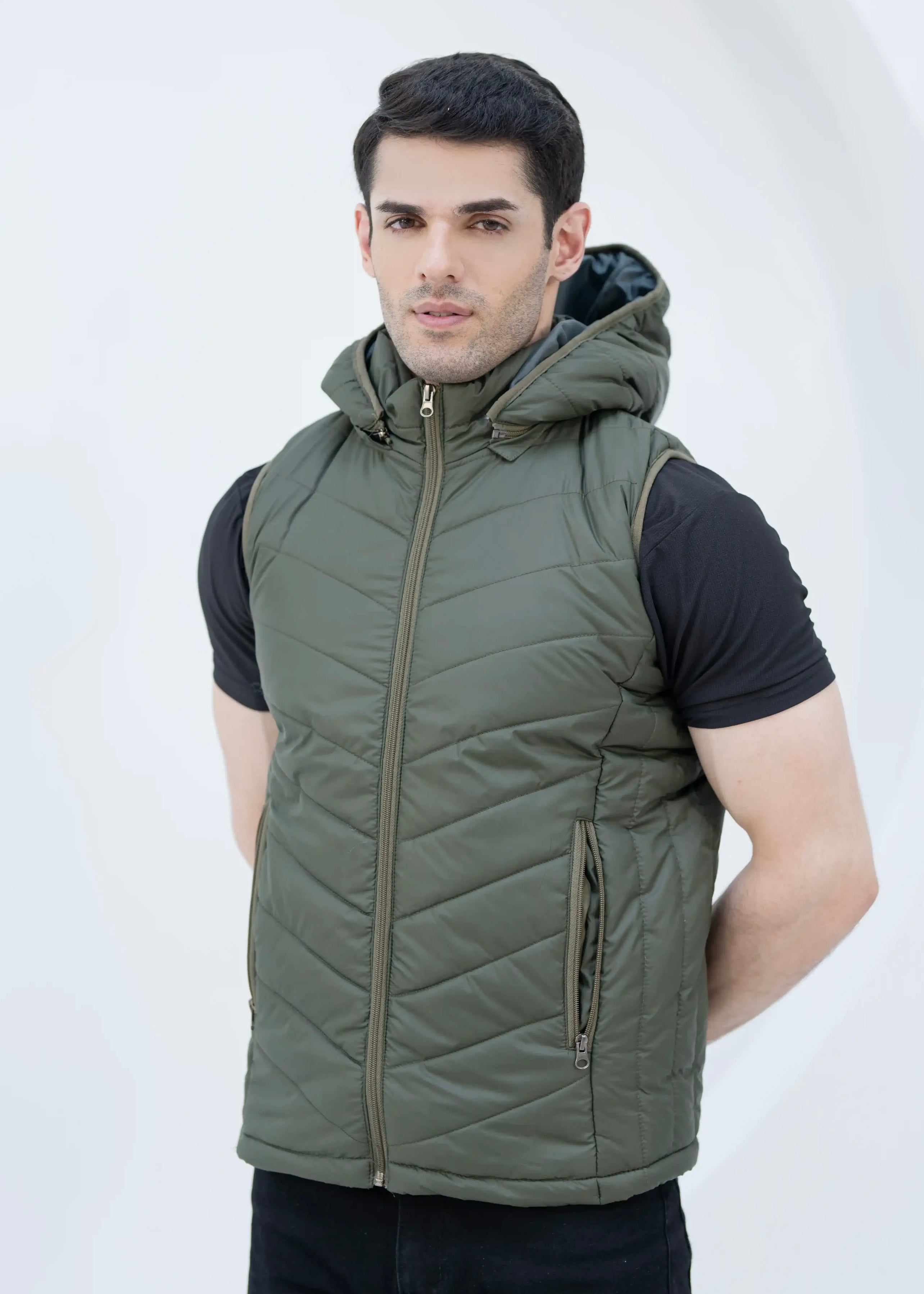 Man wearing a green quilted vest with removable hood